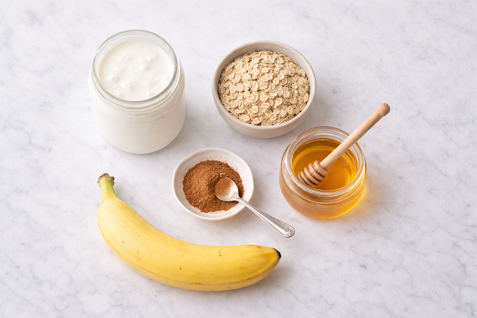 Ingredientes vitamina energética: jarra kefir branco, tigela aveia flocos, pote mel dourado, canela pó, banana madura sobre bancada mármore clara minimalista